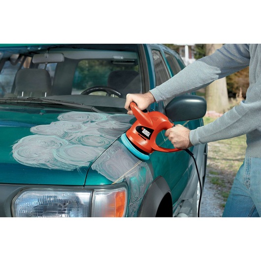 BLACKDECKER WP900 polisher being used on a green car hood, applying polish in circular patterns outdoors.